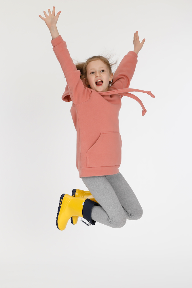 Child model posing with boots and jumping for joy